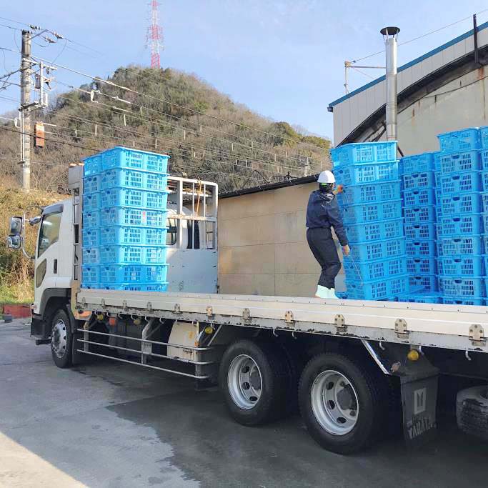 洗浄消毒したかごをトラックに積み込んでいるイメージ